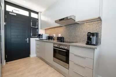 a kitchen with white cabinets and a black door at Burmeister 302 - Beach Front Views with Onsite Parking in Cape Town
