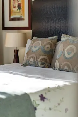 a bedroom with a bed with pillows and a lamp at Skyline Serenity - Knightsbridge in Cape Town