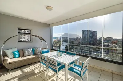 a living room with a table and chairs and a couch at Skyline Serenity - Knightsbridge in Cape Town