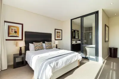 a white bedroom with a large bed and a bathroom at Skyline Serenity - Knightsbridge in Cape Town
