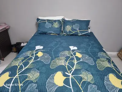 a bed with a green comforter and two pillows at 27 on Milton in Cape Town