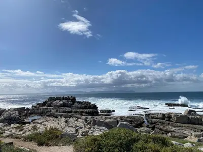a beach with rocks and waves in the ocean at Whale Rock Estate Four 1 in Hermanus