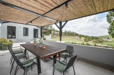 a wooden table and chairs on a patio with a view at 4 Bedroom Farm House in Brackenfell