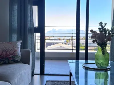 a living room with a vase of flowers on a glass table at Protea house in Cape Town