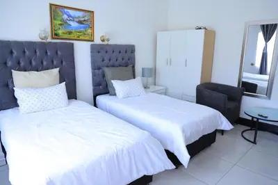 a bedroom with two beds and a chair at paradise guest house in Cape Town