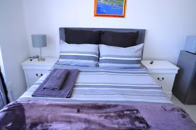 a bed with a purple and white blanket on it at paradise guest house in Cape Town
