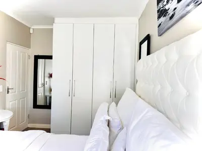 a white bedroom with a large white headboard at Luxury 2bedrooms house in Cape Town