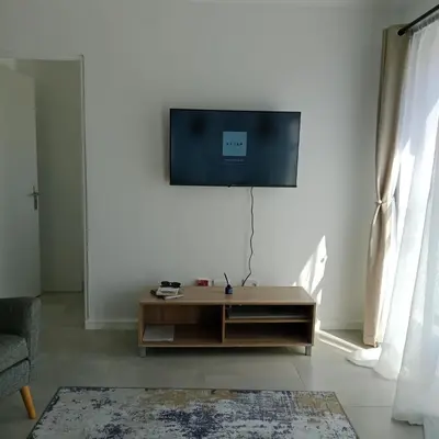 a living room with a tv on a white wall at The Cozy Nest in Cape Town