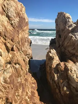 a view of the beach from between two large rocks at Otter Cottage in Pringle Bay in Pringle Bay