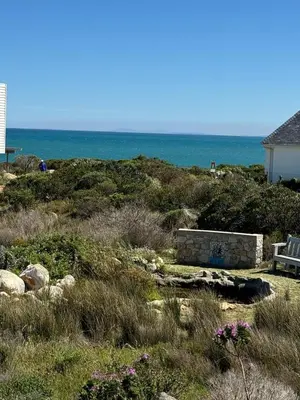 a bench sitting on top of a hill near the ocean at Otter Cottage in Pringle Bay in Pringle Bay