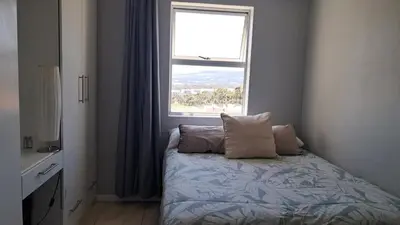 a bedroom with a bed with two pillows and a window at Gordon's bay - Sea view apartment in Cape Town