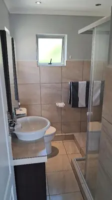 a bathroom with a sink and a toilet and a window at Gordon's bay - Sea view apartment in Cape Town