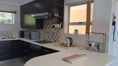 a kitchen with black cabinets and a white counter top at Gordon's bay - Sea view apartment in Cape Town