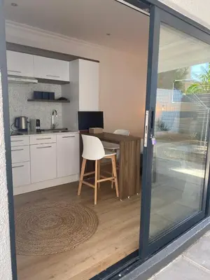 a kitchen with a table with a white chair in it at Zonnekus Guesthouse in Cape Town