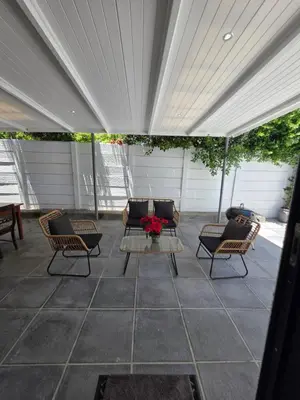 acovered patio with chairs and a table with flowers on it at Zonnekus Guesthouse in Cape Town