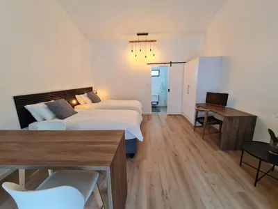 a bedroom with two beds and a table and a desk at Zonnekus Guesthouse in Cape Town