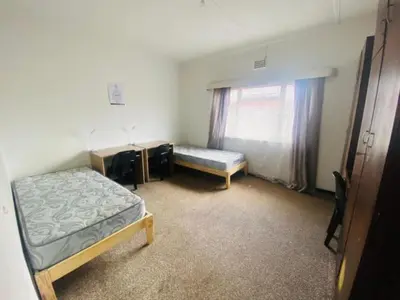 a room with two beds and a desk and a window at Eliot TM in Cape Town