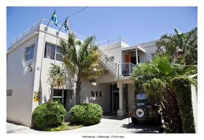 a white building with palm trees in front of it at Lifehouse in Hermanus