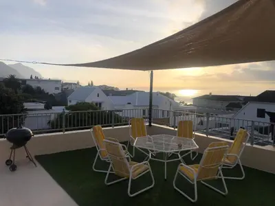 a patio with a table and chairs on a balcony at Lifehouse in Hermanus