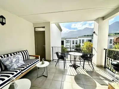 a living room with a couch and a table on a balcony at Le Bourgette - Close to Town With Great Views in Franschhoek