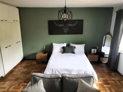 a bedroom with a large white bed and a green wall at Sunny Mountain View in Stellenbosch