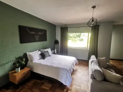 a bedroom with a large bed and a couch at Sunny Mountain View in Stellenbosch