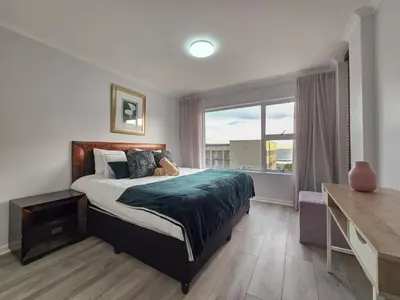 a bedroom with a bed and a large window at Spacious 3Bed 2bath sleep 8 Beachfront Apartment with Table Mountain and Ocean view in Cape Town