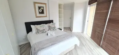a bedroom with a bed with white sheets and pillows at Spacious 3Bed 2bath sleep 8 Beachfront Apartment with Table Mountain and Ocean view in Cape Town