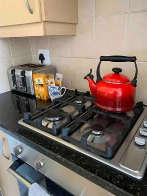 a red tea kettle is sitting on a stove at Spacious 3Bed 2bath sleep 8 Beachfront Apartment with Table Mountain and Ocean view in Cape Town
