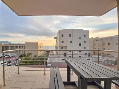 a wooden bench on a balcony with a table at Spacious 3Bed 2bath sleep 8 Beachfront Apartment with Table Mountain and Ocean view in Cape Town
