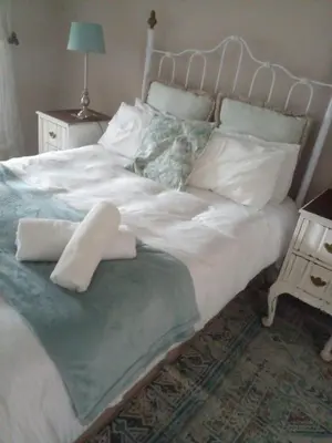 a large bed with white sheets and pillows on it at Johannies Home at Panorama Hospital in Cape Town