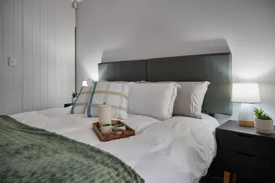 a bedroom with a large bed with white sheets and pillows at Peppertree Place in Cape Town