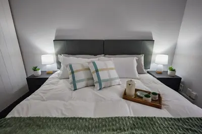a white bed with two lamps and a tray on it at Peppertree Place in Cape Town