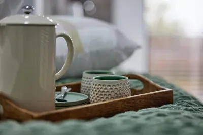 a tray with a tea kettle and cups on a bed at Peppertree Place in Cape Town