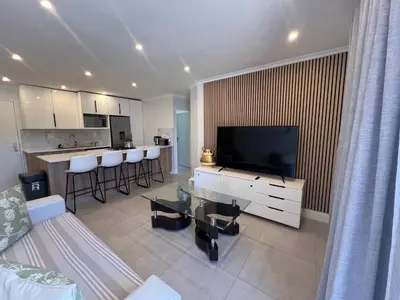 a living room with a large television and a kitchen at 4 sleeper Lamsyh Apartment in Cape Town