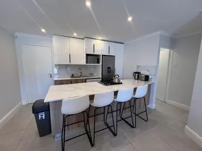 a kitchen with a island with bar stools at 4 sleeper Lamsyh Apartment in Cape Town