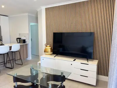 a living room with a large television on a wall at 4 sleeper Lamsyh Apartment in Cape Town
