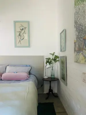a bedroom with a bed and a table and pictures at Stellenbosch Farm Studio Apartment in Penhill