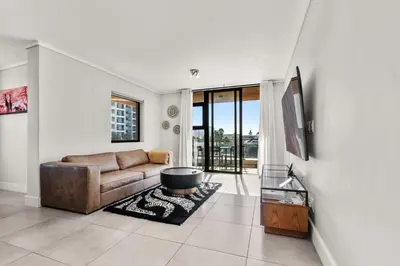 a living room with a couch and a table at Waters Edge Luxury Apartment Century City in Cape Town