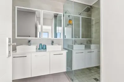 a white bathroom with two sinks and a mirror at Waters Edge Luxury Apartment Century City in Cape Town