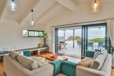 a living room with a couch and a large window at SeaScape Silversands in Bettyʼs Bay