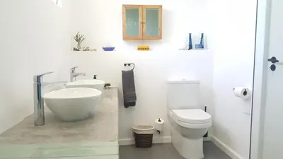a white bathroom with a sink and a toilet at SeaScape Silversands in Bettyʼs Bay
