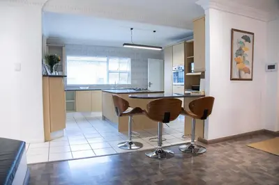 a kitchen with a table and some chairs in it at Vredekloof Views in Cape Town