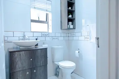 a bathroom with a white toilet and a sink at Vredekloof Views in Cape Town