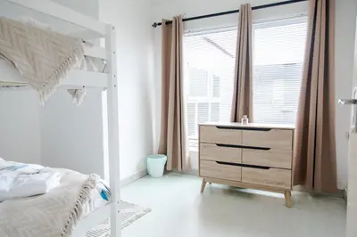 a bedroom with a bed and a dresser and a window at Vredekloof Views in Cape Town