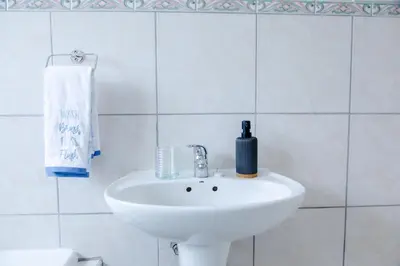 a white sink in a white tiled bathroom at Vredekloof Views in Cape Town