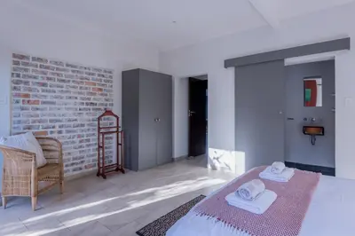 a bedroom with a bed and a chair and a brick wall at 2stay Apartment Protea - Cape Town Bloubergstrand in Cape Town