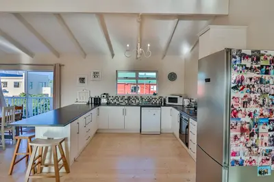 a kitchen with white cabinets and a refrigerator at Tides in Bettyʼs Bay