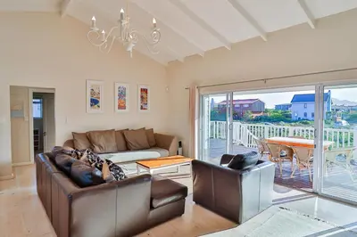 a living room with a couch and chairs and a table at Tides in Bettyʼs Bay