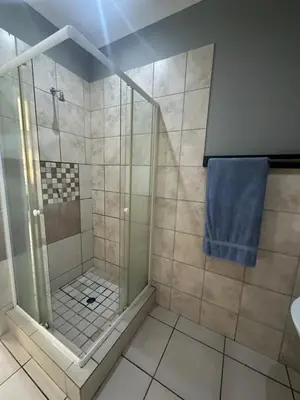a bathroom with a shower with a blue towel at Cute Tranquil Pool Side Apartment in Cape Town